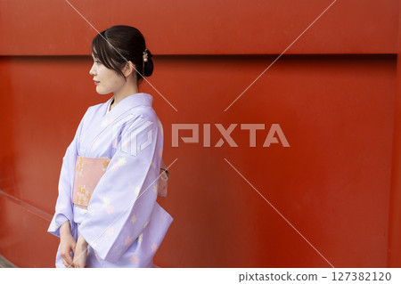一位身著日本傳統服裝的日本女性站在神社朱紅色牆壁前 127382120