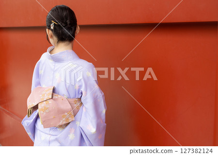 一位身著日本傳統服裝的日本女性站在神社朱紅色牆壁前 127382124