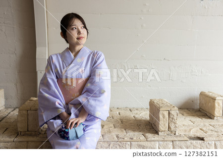 一位穿著和服的日本年輕女子坐在長椅上 127382151