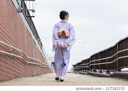 Back view of a young woman in a kimono walking down the street Back view of a young woman in a kimono walking down the street 127382155