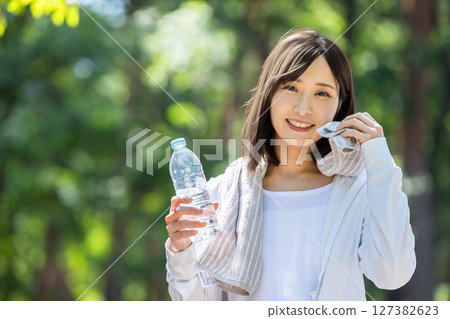 一位女士用毛巾擦汗並補充水分 127382623