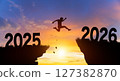 Welcome merry Christmas and Happy new year in 2026. Man jumping across the gap from 2025 to 2026 cliff with Sunset and Twilight Sky background. 127382870