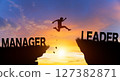 Silhouette man jumping from MANAGER to LEADER wording on cliffs with cloud sky and sunrise. Go ahead and Keep go on to success Concept. 127382871
