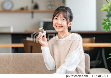 Elementary school, junior high school, and high school girls holding bottles of medicine and supplements 127383021