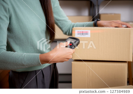 Closeup hand of woman scanning package with barcode reader in office. Closeup hand of woman scanning package with barcode reader in office. 127384989