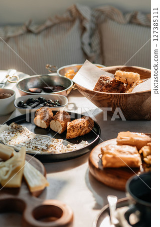 Traditional Turkish breakfast table with bread, cheese, olives and spreads in natural morning light Traditional Turkish breakfast table with bread, cheese, olives and spreads in natural morning light 127385111