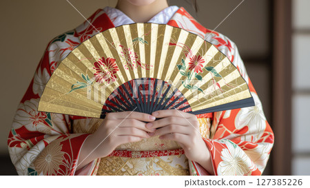 Woman in traditional kimono holding a golden fan 127385226