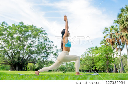 Asian woman practicing yoga outdoors in a green park Asian woman practicing yoga outdoors in a green park 127386064