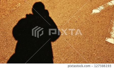 Shadow of a person holding a camera 127386193