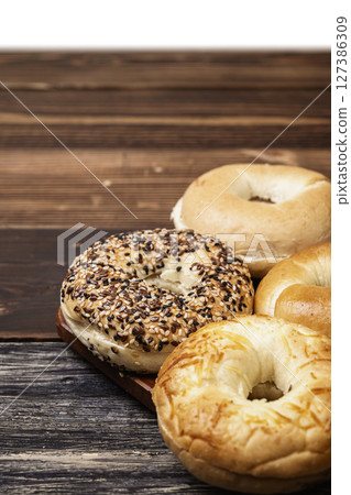 Closeup view of a collection of bagel breads with various kinds on a wooden board isolated over a white background Closeup view of a collection of bagel breads with various kinds on a wooden board isolated over a white background 127386309