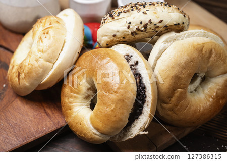 Closeup view of a variety of kinds of bagel breads with sliced bagel bread on a wooden board 127386315
