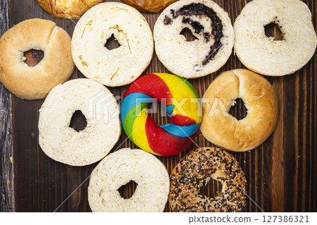 Closeup view of a variety of kinds of bagel breads with bagel bread sliced on a wooden board. Top view 127386321