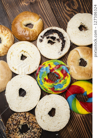 Closeup view of a variety of kinds of bagel breads with bagel bread sliced on a wooden board. Top view Closeup view of a variety of kinds of bagel breads with bagel bread sliced on a wooden board. Top view 127386324