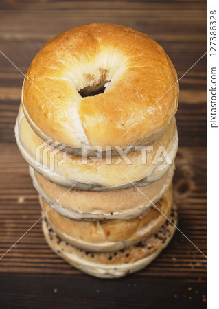 Closeup view of a pile of a collection of bagel breads with various kinds on a wooden board 127386328