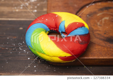 Closeup view of a rainbow bagel bread on a wooden board 127386334