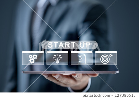 Businessman is showing an icon of a startup on the tablet screen. Technology innovation on a virtual screen. Concept of business startup Businessman is showing an icon of a startup on the tablet screen. Technology innovation on a virtual screen. Concept of business startup 127386513
