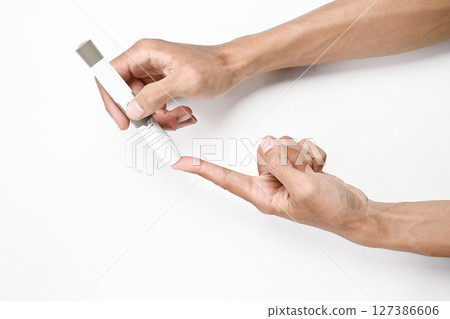 Human hand using a lancet for checking blood sugar level isolated over a white background. Concept of diabetes or a healthy lifestyle Human hand using a lancet for checking blood sugar level isolated over a white background. Concept of diabetes or a healthy lifestyle 127386606