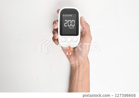 Human hand holding a glucometer for checking blood sugar level isolated over a white background. Concept of diabetes or a healthy lifestyle Human hand holding a glucometer for checking blood sugar level isolated over a white background. Concept of diabetes or a healthy lifestyle 127386608