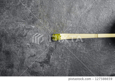 Traditional bamboo spoon or chashaku with matcha green tea powder on a black table. Accessories for making matcha green tea. Top view 127386659