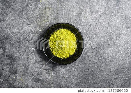 Closeup view of matcha green tea powder in the black bowl on a black table. Top view 127386660