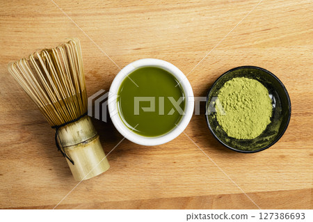 Matcha green tea and a traditional bamboo brush whisk or chasen on a table. Accessories for making matcha green tea. Top view Matcha green tea and a traditional bamboo brush whisk or chasen on a table. Accessories for making matcha green tea. Top view 127386693