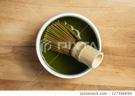 Matcha green tea whipped with a traditional bamboo brush whisk or chasen on a table. Accessories for making matcha green tea. Top view Matcha green tea whipped with a traditional bamboo brush whisk or chasen on a table. Accessories for making matcha green tea. Top view 127386694