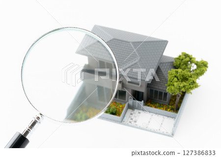 Magnifying glass and miniature detached house on white background 127386833