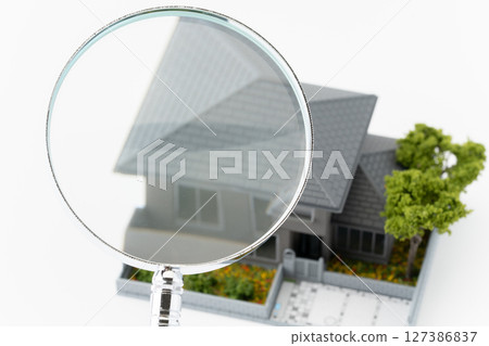 Magnifying glass and miniature detached house on white background 127386837