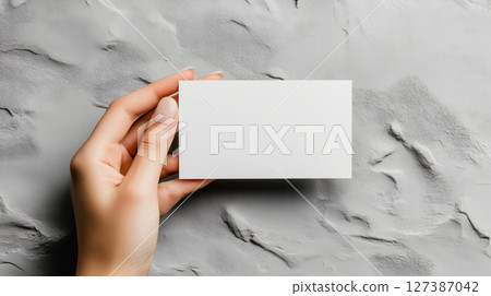 Hand holding a blank business card on a textured surface, created with Generative AI 127387042