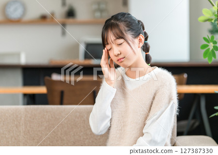 Elementary school and junior high school girls holding their temples due to headaches 127387330