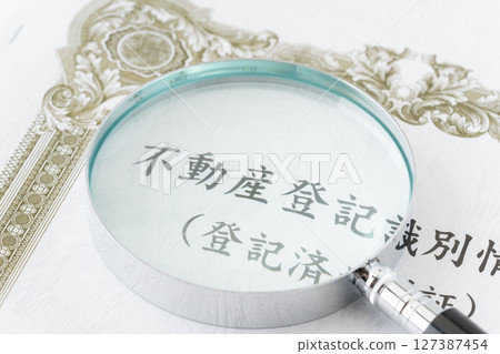 Real estate registration identification information (registered title deed) with a magnifying glass 127387454