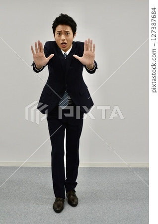 A young man giving a "stop" sign with both hands 127387684