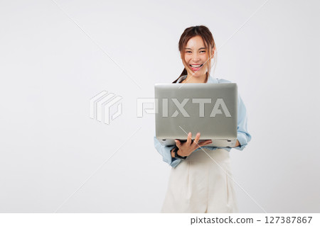 Happy young Asian woman typing on laptop computer, smiling open mouth and excited about work, multitasking on another laptop while focusing on creative business tasks. isolated studio white background Happy young Asian woman typing on laptop computer, smiling open mouth and excited about work, multitasking on another laptop while focusing on creative business tasks. isolated studio white background 127387867