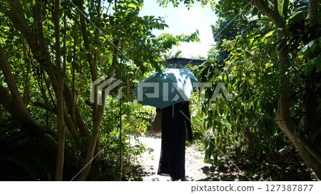 A woman walking along a narrow road on Yubu Island 127387877