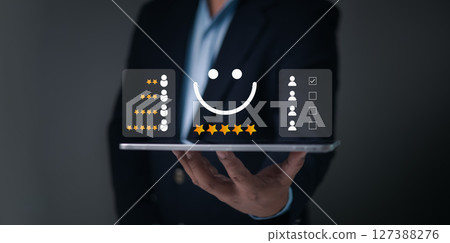 Customer rating icons, Businessman holds a tablet and smiley face with five stars, representing user satisfaction, service quality feedback, client experience reviews, positive evaluation. 127388276