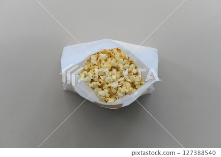 "Top-down shot of butter-flavored popcorn in a white bag on a white background." "Top-down shot of butter-flavored popcorn in a white bag on a white background." 127388540