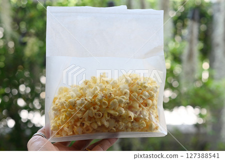 Butter-flavored popcorn in a white bag. 127388541