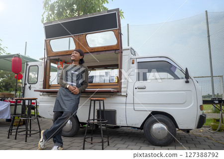 Indonesian southeast asian male barista standing with confidence in front of his coffee shop. A small business of a coffee shop or cafe on a truck 127388792