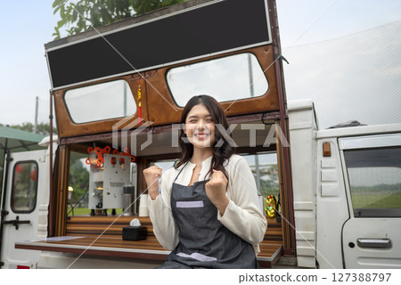 Indonesian southeast asian female barista standing with confidence in front of his coffee shop. A small business of a coffee shop or cafe on a truck 127388797