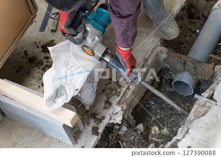 A construction worker doing piping work with an electric hammer (junk hammer) 127390088