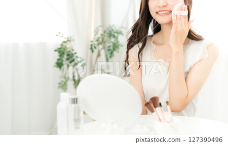 Smiling Asian woman applying foundation powder makeup 127390496