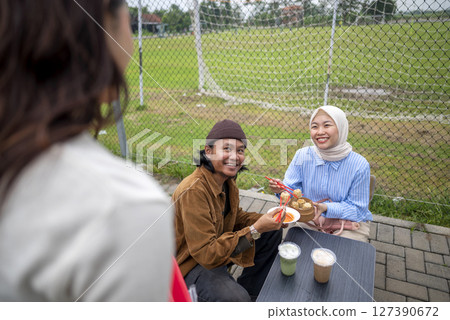 Indonesian southeast chinese asian female waiter serving food and beverage order to chinese muslim woman and man couple customer. A small business on a truck Indonesian southeast chinese asian female waiter serving food and beverage order to chinese muslim woman and man couple customer. A small business on a truck 127390672