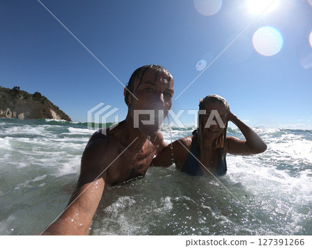 Powerful ocean waves splashing funny couple Powerful ocean waves splashing funny couple 127391266