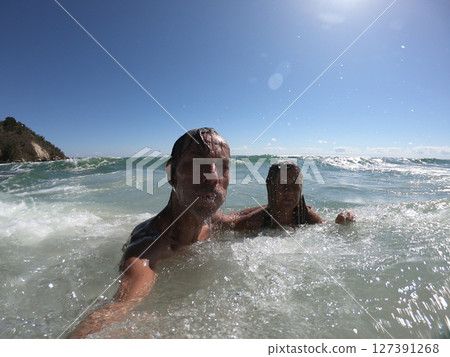 Powerful ocean waves splashing funny couple Powerful ocean waves splashing funny couple 127391268
