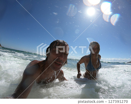 Sea waves splashing on happy couple. Sea waves splashing on happy couple. 127391270