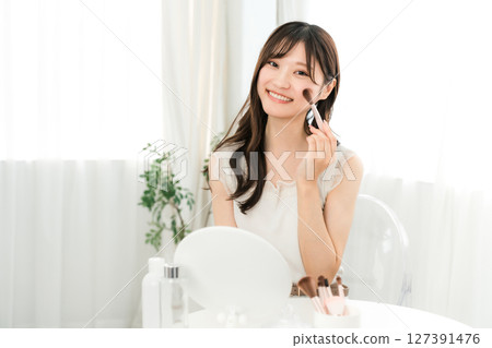 年輕的亞洲女性用腮紅刷和麵刷化妝 127391476