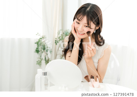 年輕的亞洲女性用腮紅刷和麵刷化妝 127391478