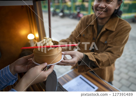Female waiter serving food to an Indonesian southeast asian man of customers. A small business on a truck 127391489
