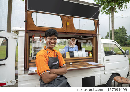 Indonesian southeast asian male and a Chinese muslim female in hijab couple baristas with confidence in their coffee shop. A small business of a coffee shop or cafe on a truck 127391499