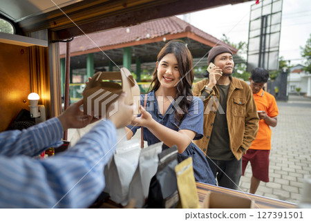 Female waiter serving food to an Indonesian southeast asian customers. A small business on a truck Female waiter serving food to an Indonesian southeast asian customers. A small business on a truck 127391501